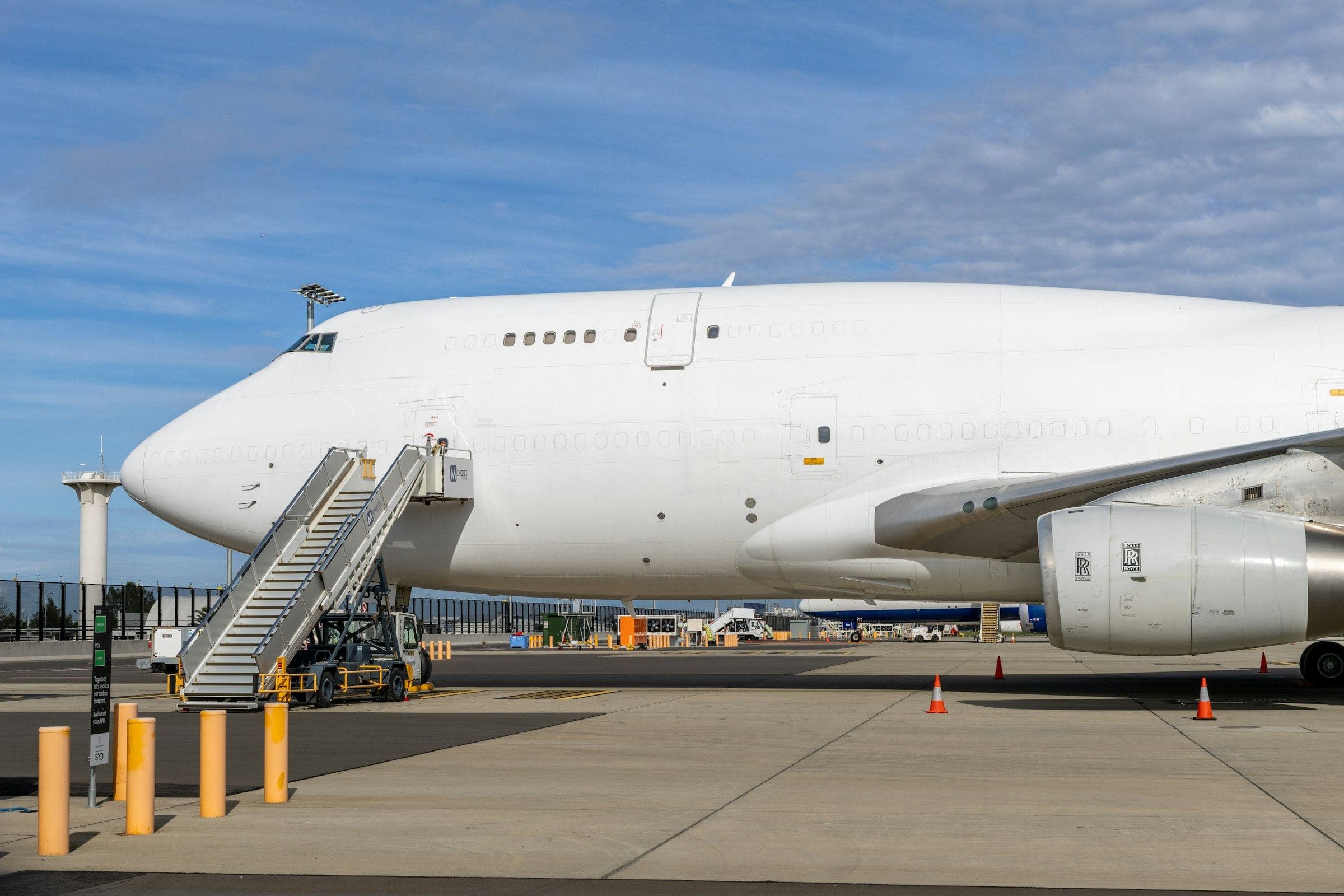 Large white cargo aircraft parked on the apron with boarding stairs