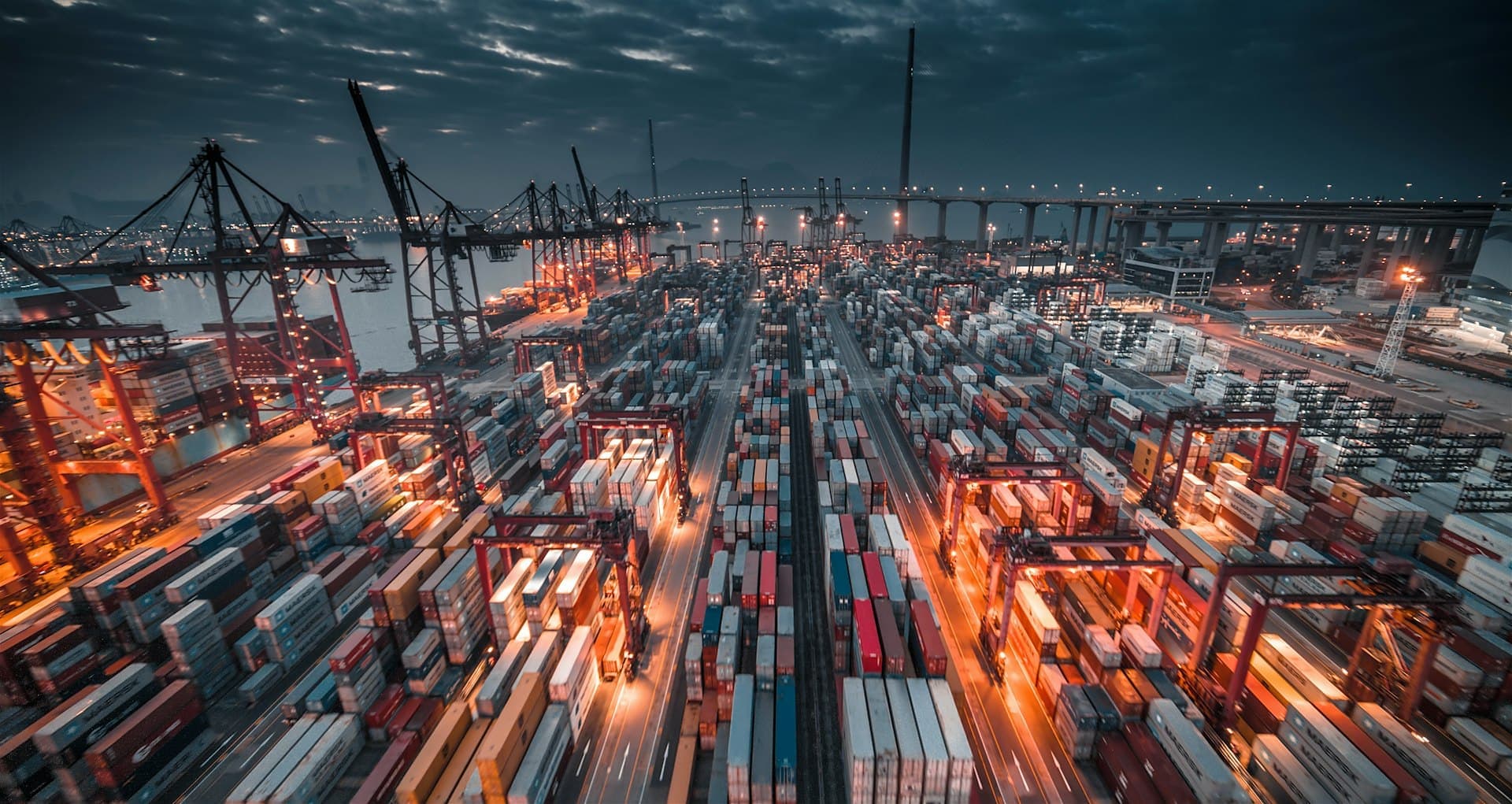 Container terminal lit up at night beneath ship-to-shore cranes
