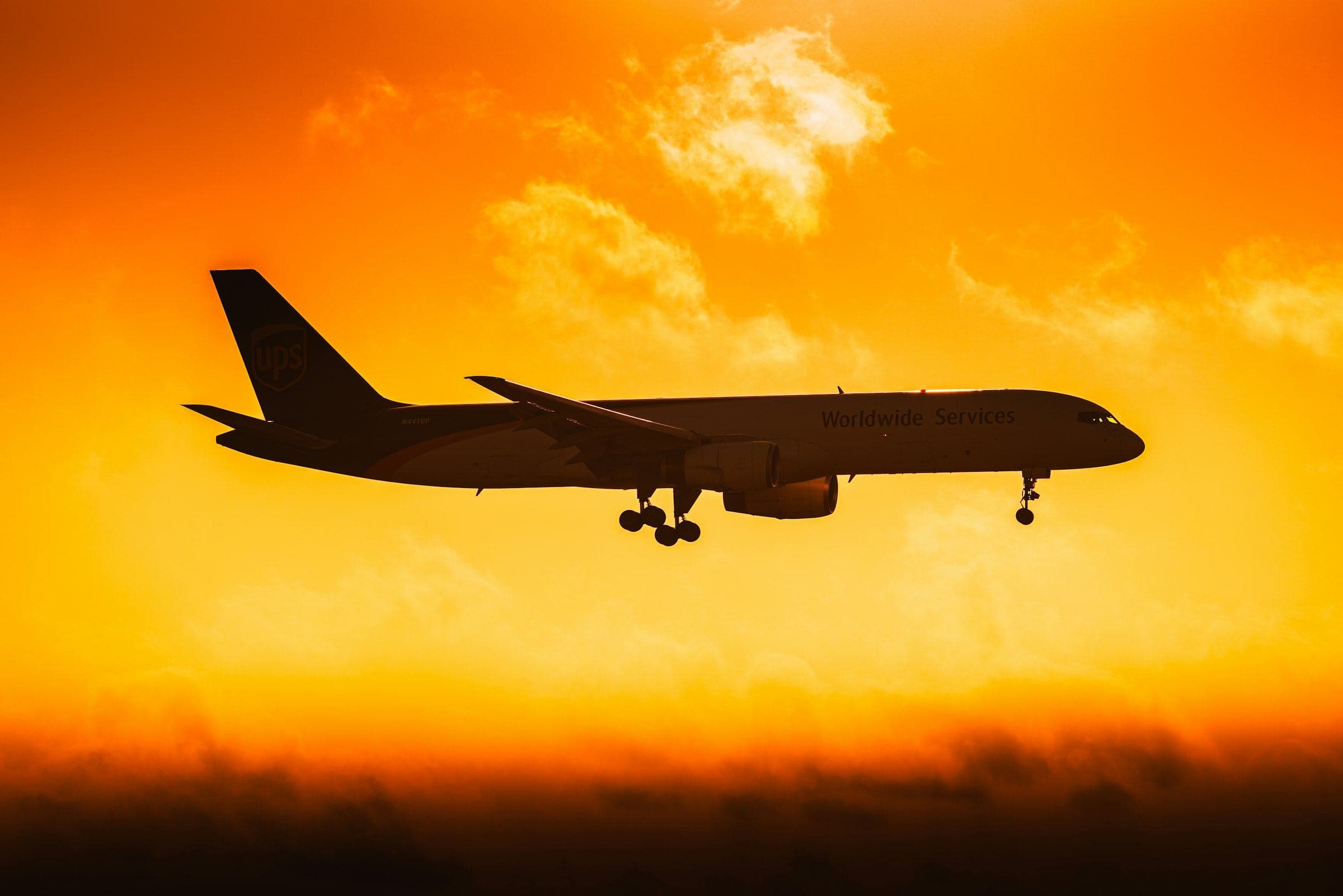 Cargo aircraft silhouetted against an orange sunset